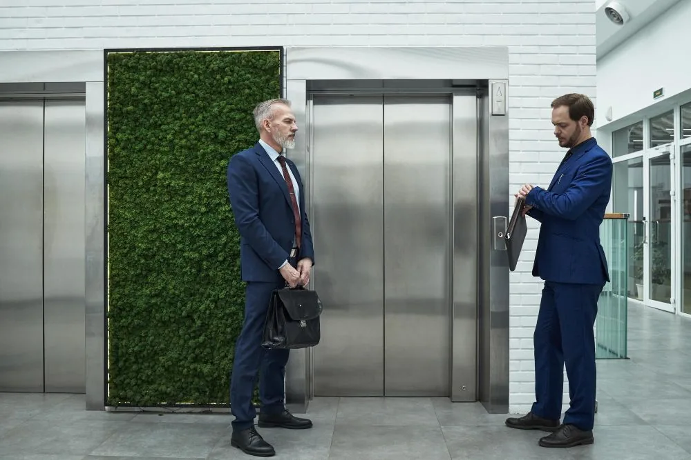 Modernised office lift lobby with stainless doors and green wall